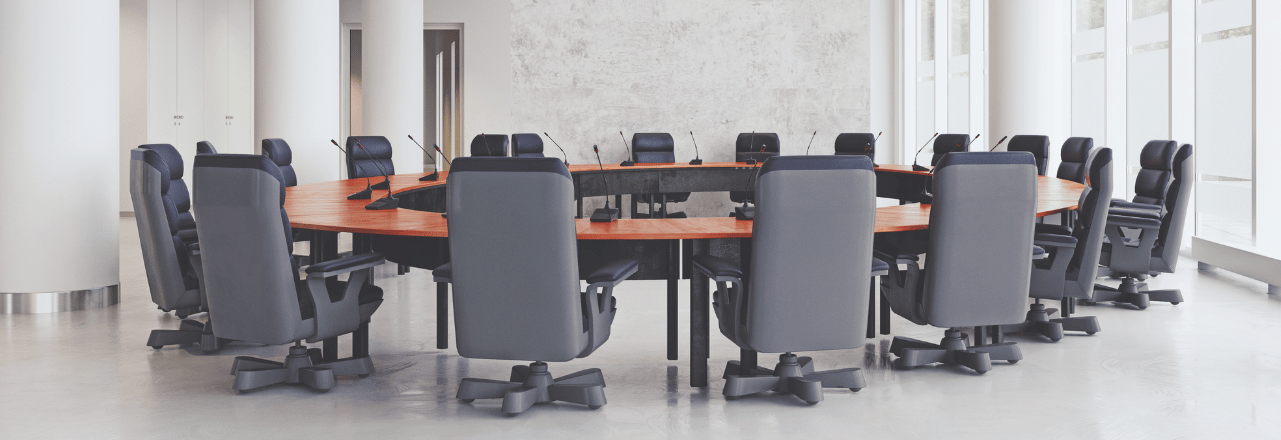 une salle de réunion vide avec des murs en béton blanc. un bureau circulaire vide au centre, avec plus de 20 chaises d'ordinateur vides. 