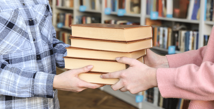 person handing off books to another person
